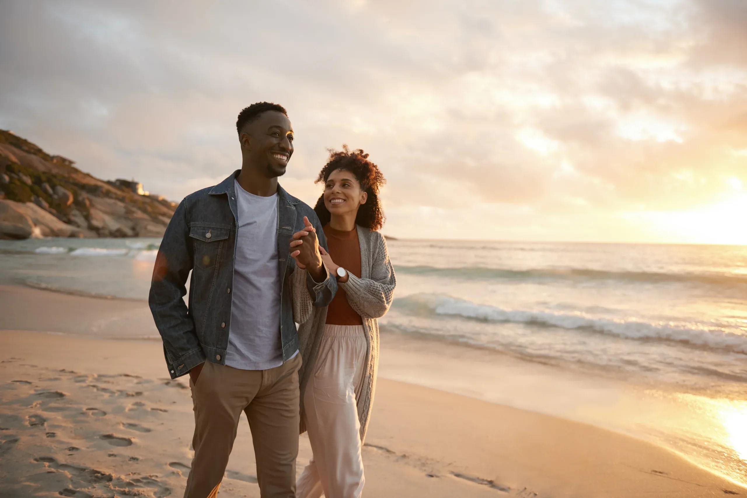 A couple walking hand in hand on a San Diego beach at sunset